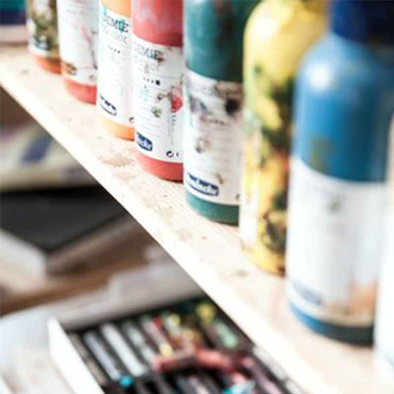 Colourful paint bottles displayed on a shelf.